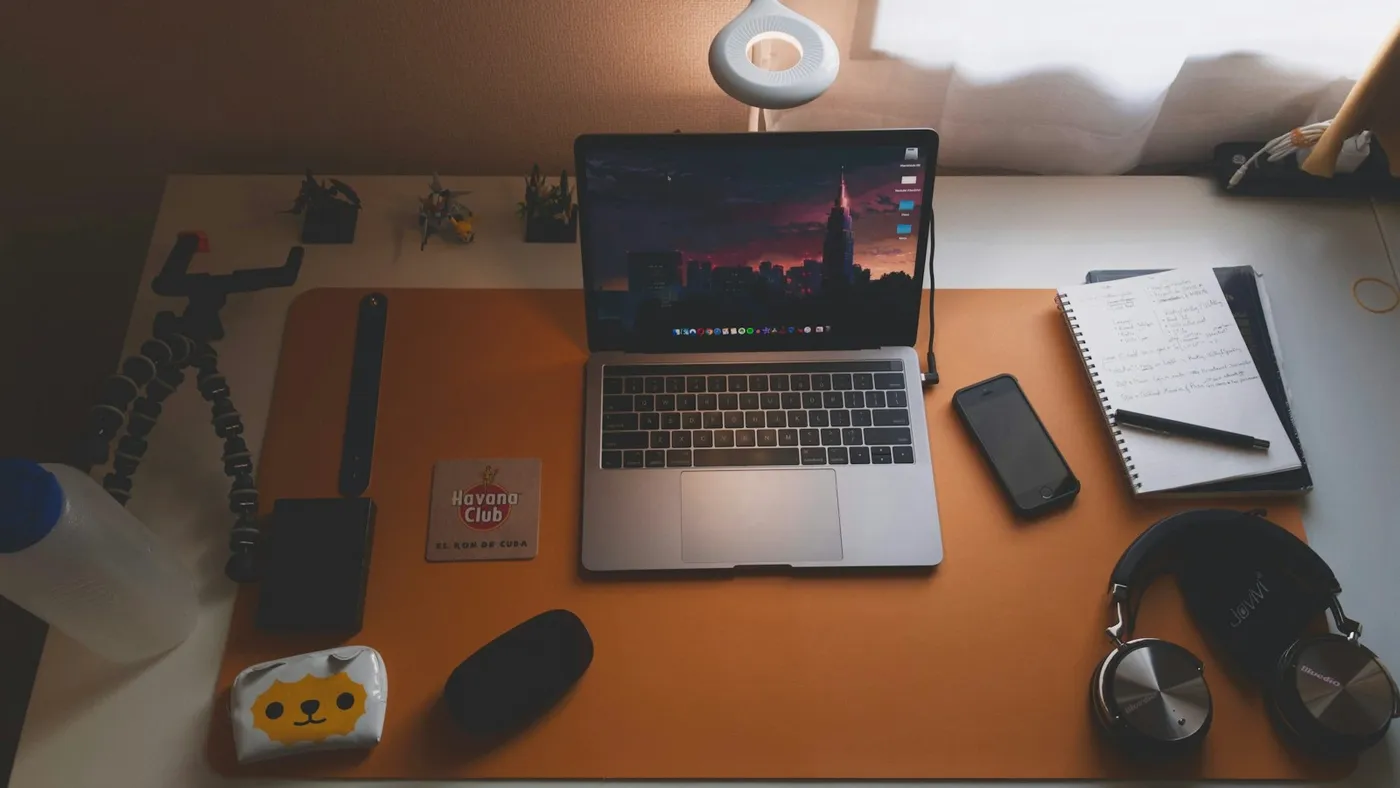 A desk from above: laptop, phone, notebook