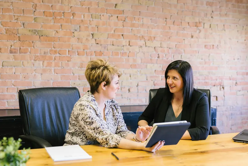 Two partners at a brick-wall office reviewing a tablet together