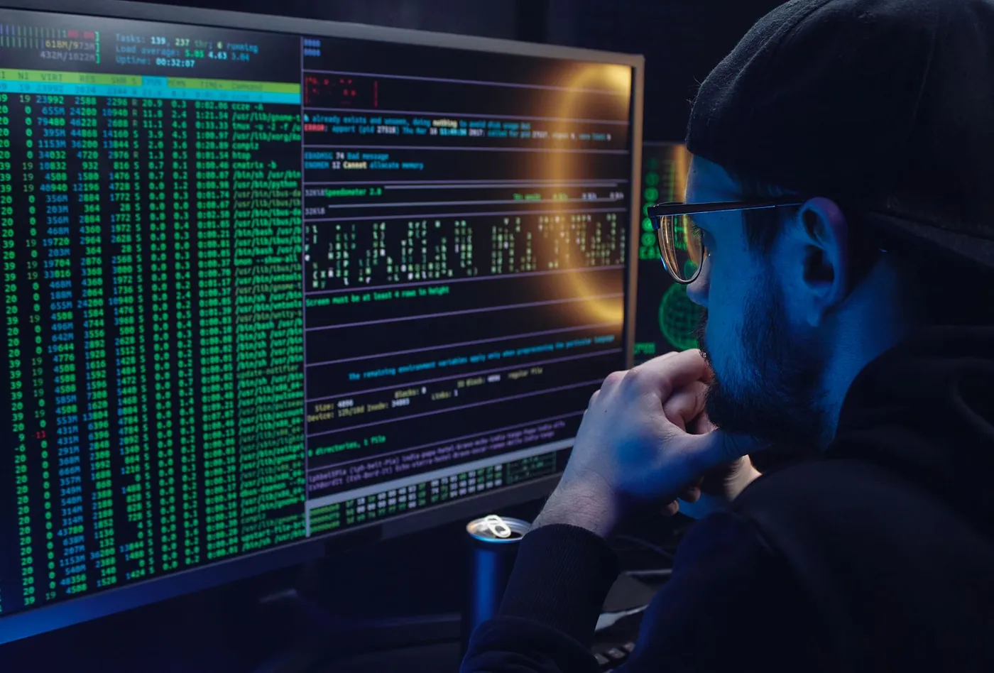 Engineer reading process lists and error output on two monitors while auditing an inherited codebase